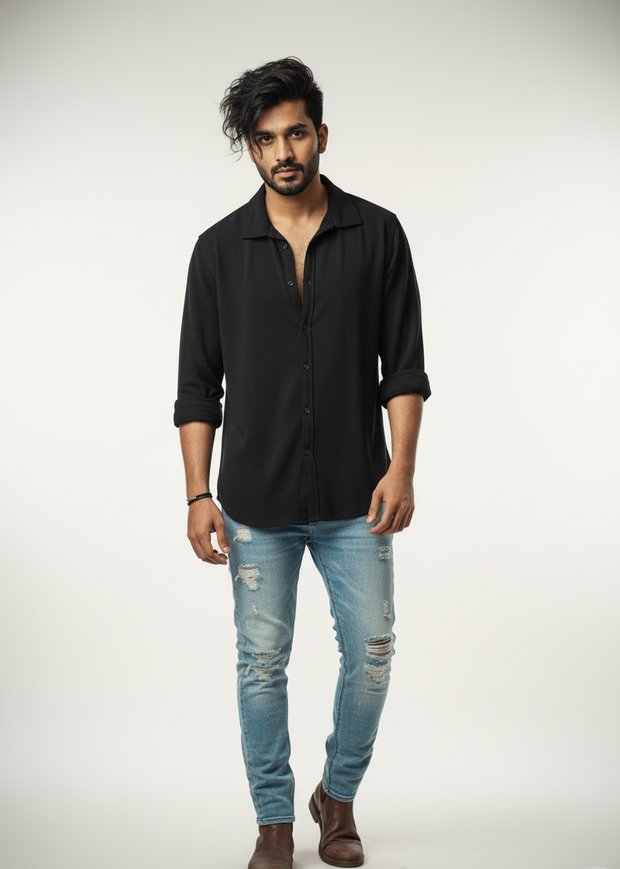 Man wearing a black shirt and light blue jeans on a white background